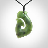 This picture shows a jade hook pendant, also called a hei-matau, carved for us in New Zealand jade. The cord is a four-plait, adjustable black coloured necklace.