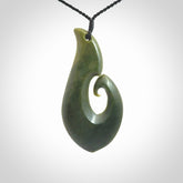This picture shows a hand carved jade koru pendant. It is a deep green colour and is a wonderful, large sized piece of jewellery. The cord is a four plait black colour and adjustable so that you can position the pendant where it suits you best. This koru was carved for us by Ric Moor. Delivery is free worldwide.