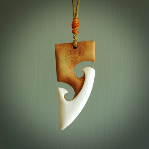 A hand carved bone toki with double koru, intricate pendant. The cord is a tan colour and is adjustable. A medium sized hand made toki with koru necklace by New Zealand artist Tonijae Brockway. Tonijae has stained parts of the bone which really add to the dimension of this pendant. One off work of art to wear.