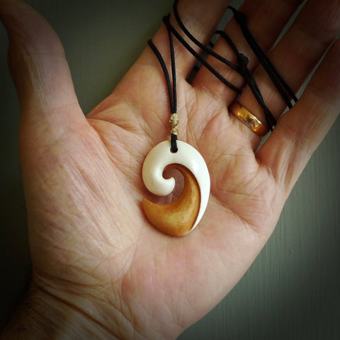 A hand carved bone contemporary, koru pendant. The cord is black colour and is adjustable. A medium sized hand made contemporary koru necklace by New Zealand artist Tonijae Brockway. Tonijae has stained parts of the bone which really add to the dimension of this pendant. One off work of art to wear.
