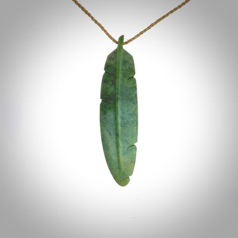 A hand carved large New Zealand Jade feather necklace. The cord is a tan colour and is a fixed length. A large sized hand made Jade feather necklace by New Zealand artist Kerry Thompson. One off work of art to wear.