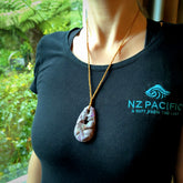 A large and beautiful hand carved partner hoongi pendant in sugilite. This piece is carved from purple Sugilite stone by Jeromy Van Riel with opal and rubys. This is a wonderful work of art to wear and comes with a hand-plaited cord and a bone toggle. A beautiful, unique pendant by Jeromy Van Riel for sale online.