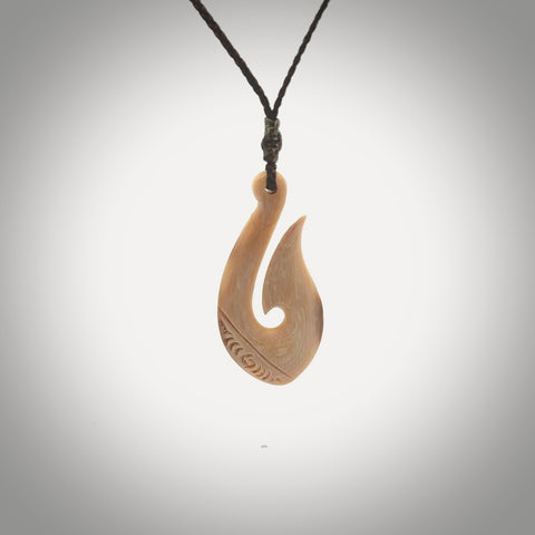 A fish hook necklace (hei-matau) hand-carved in a traditional style from Woolly Mammoth Tusk. Delivered on an adjustable cord in one of our kete pouches.