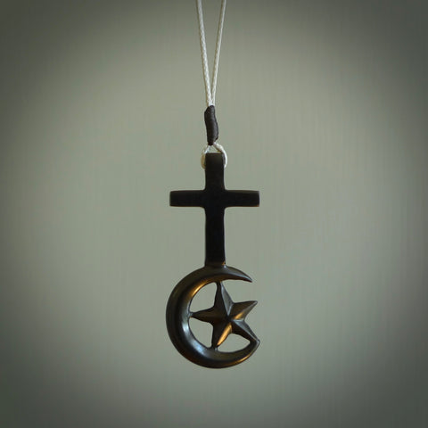 This pendant is a series of religious symbols carved in one piece of black jade. The top is a christian cross and at the bottom is the crescent of islam. It is suspended on a snowstorm grey plaited cord which is length adjustable.