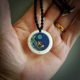 This photo shows a medium sized yin and yang pendant hand carved from bone with New Zealand Pounamu Jade, Lapis Lazuli and Paua Shell inlay alongside; brass and silver. This is a stand out one off necklace for those who appreciate art to wear. It is provided with a cord in black that is a fixed length with Paua Shell Toggle. We ship this piece worldwide and shipping is included in the price.