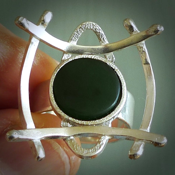 This is a handcrafted New Zealand Pounamu, Jade and sterling silver ring. This is a solid little work of art. We ship this worldwide for free and are happy to answer any questions that you may have about these or other products on our website. Hand carved by Ana Krakosky. Delivered with Express Courier in a woven kete pouch.