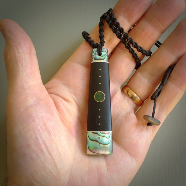 This photo shows a medium sized Toki pendant hand carved from antique elephant statue with New Zealand Pounamu, Green Stone, and Paua Shell inlay alongside; brass and silver. This is a stand out one off necklace for those who appreciate art to wear. It is provided with a cord in black that is a fixed length with Paua Shell Toggle. We ship this piece worldwide and shipping is included in the price.