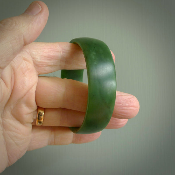 Hand carved jade bangle. Carved from green New Zealand jade. This is a solid jade bangle carved from a single piece of jade. It is polished to a sleek matte. the jade is otherwise untreated and completely natural.