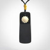 Black Jade toki pendant with bone flower. We've bound it with an adjustable black cord and yellow floret.