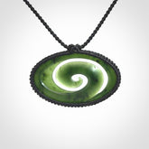 This picture shows a medium sized hand carved jade koru pendant. It is a darker green colour which is quite translucent where the jade is thin. The cord is bound in a macrame style and is adjustable so that you can position the pendant where it suits you best.