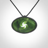 This picture shows a medium sized hand carved jade koru pendant. It is a darker green colour which is quite translucent where the jade is thin. The cord is bound in a macrame style and is adjustable so that you can position the pendant where it suits you best.