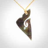 This photo shows a matau, hook, pendant carved from New Zealand Totoweka Pounamu, Jade. We provide this piece with an adjustable beige coloured cord.