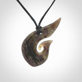 This photo shows a contemporary koru pendant carved from New Zealand Totoweka Jade. We provide this piece with a black fixed length cord.