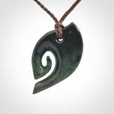 This photo shows a koru pendant carved from New Zealand Jade. We provide this piece with an adjustable brown cord.