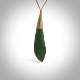 This photo shows a beautiful large jade drop. It is handcarved from a piece of green New Zealand pounamu, with fascinating light green inclusions throughout the stone. We have this on a creme coloured, adjustable four plait cord. We ship this worldwide with an express courier service. Postage is free.