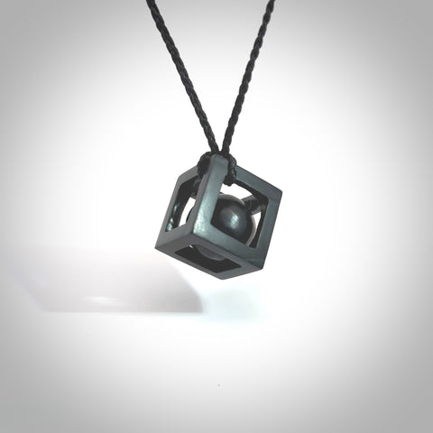 A hand carved large Black Jade square box with ball inside necklace. The cord is black and adjustable in length. A medium sized hand made box necklace in Australian Black Jade. One off work of art to wear.