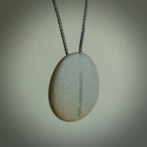 Greywacke stone pendant with New Zealand Jade Pounamu insert. Hand carved by Rhys Hall for NZ Pacific. Handmade jewellery for sale online. Delivered to you with express courier in one of our kete pouches.