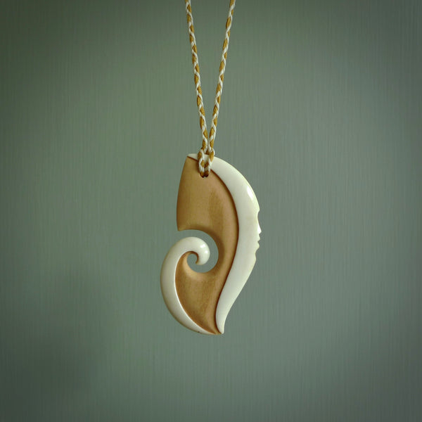 A hand carved bone contemporary, intricate pendant. The cord is ice white and burnt gold and is an adjustable length. A large sized hand made contemporary necklace by New Zealand artist Kerry Thompson. Kerry has stained parts of the bone which really add to the dimension of this pendant. One off work of art to wear.