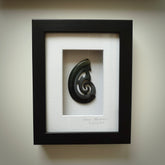 A hand carved large New Zealand Jade Hook, Matau, necklace that has been framed and signed by artist Kerry Thompson. A large sized hand made hook necklace by New Zealand artist Kerry Thompson. One off framed work of art to wear. Delivered with Express Courier.