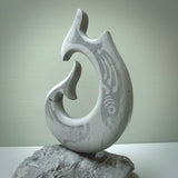 Hand carved large New Zealand Argillite Stone Matau, hook carving displayed in a New Zealand Pākohe stand sculpture. Hand carved here in New Zealand by Kerry Thompson. This is a 'one only' sculpture, a beautiful display piece.