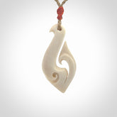 Hand carved bone hook pendant hand made by Peter Mitchell in New Zealand. This bone hook is provided with an adjustable Kalahari cord and packaged in a woven kete pouch. Free delivery worldwide.
