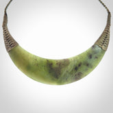 This picture shows a hand carved New Zealand jade contemporary half-shield pendant. It is a semi-transluscent green colour and is a wonderful, large piece of jewellery. The cord is hand plaited and adjustable so that you can position the pendant where it suits you best. This piece was carved for us by Donna Summers.
