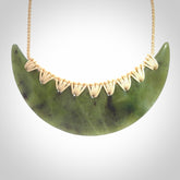This picture shows a hand carved jade contemporary half-shield pendant. It is a semi-transluscent green colour. The cord is hand plaited and adjustable so that you can position the pendant where it suits you best.