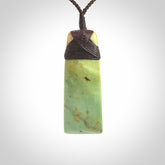 Hand carved from a lovely piece of local New Zealand flower Jade. We have suspended this from a 4-plait brown cord which can be adjusted with a couple of slip knots and brown binding.