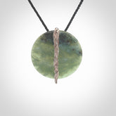 Hand carved New Zealand Inanga circle disc drop with sterling silver shard pendant. Made by Ana Krakosky for NZ Pacific in New Zealand Pounamu, jade. A beautiful light and varied green Inanga Pounamu, jade medium sized circle disc, drop necklace with silver cast insert, provided on a black adjustable cord.