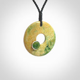 Hand carved New Zealand flower Jade disc drop pendant with smaller pounamu and silver insert. Made by Ana Krakosky for NZ Pacific in New Zealand Pounamu, jade. A beautiful orange and green jade disc necklace with black adjustable cord.