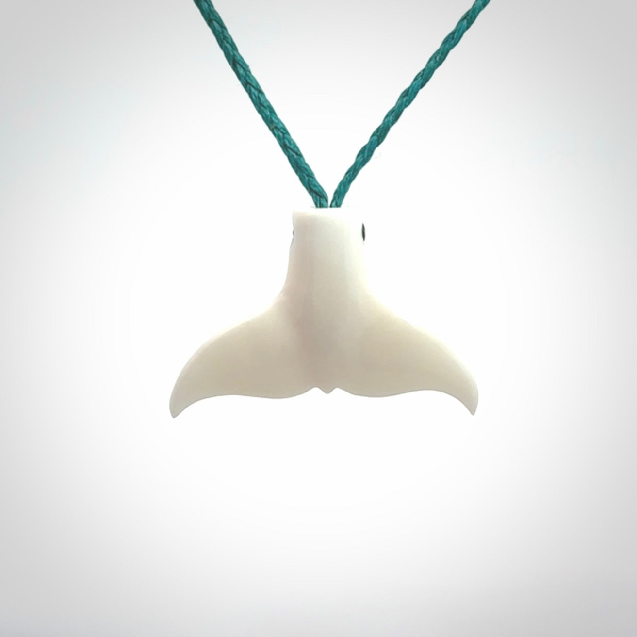 This is a lovely little Dolphin tail pendant. We have hand carved this in a bright, white bone and we make the necklace from a hand-plaited waxed cord. These are original NZ Pacific pendants, handmade from natural materials.