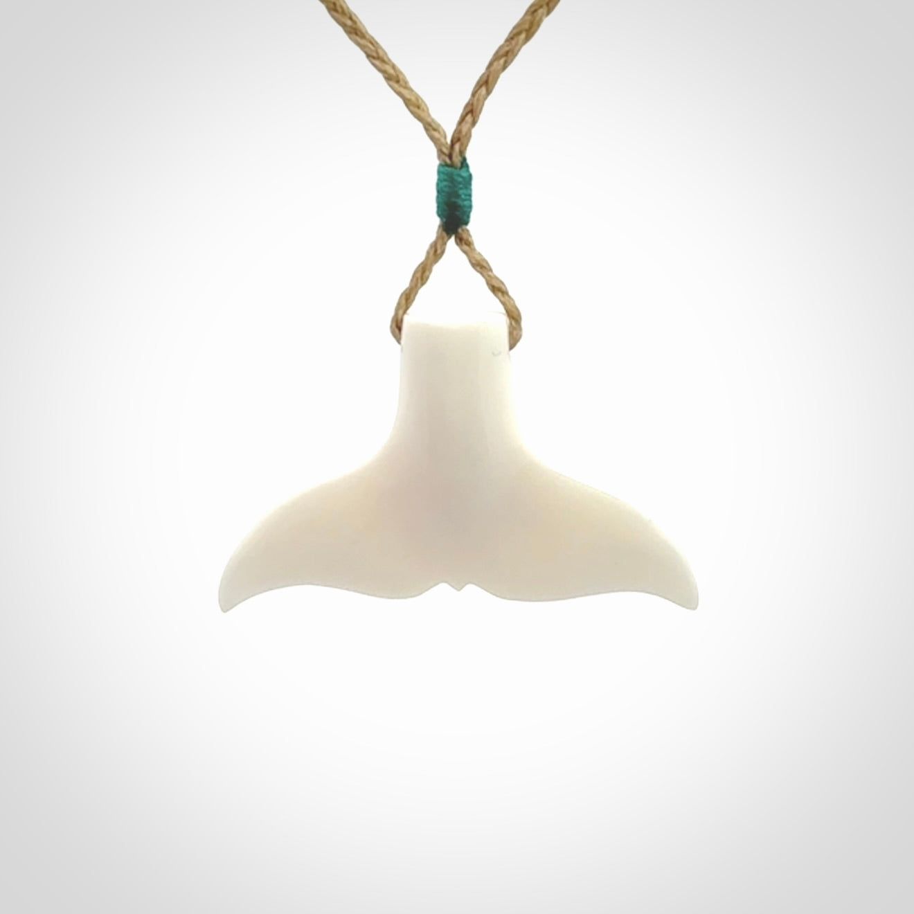 This is a lovely little Dolphin tail pendant. We have hand carved this in a bright, white bone and we make the necklace from a hand-plaited waxed cord. These are original NZ Pacific pendants, handmade from natural materials.