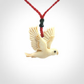 This picture shows a carved kea pendant in bone. It is provided with a hand-plaited red cord that is length adjustable. Shipping is included and we ship worldwide.