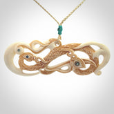 This picture shows a carved double manaia in bone. The artist has carved traditional decorative Koru designs into the face of the body and these run up the sides of the manaia head. These have specific meanings. It is provided with a hand-plaited oat cord that is length adjustable.