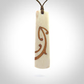 A hand carved, double sided, bone toki with triple koru, intricate pendant. The cord is a marrakesh colour and is adjustable.