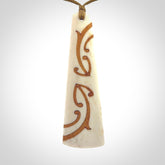 A hand carved, double sided, bone toki with triple koru, intricate pendant. The cord is a camel colour and is adjustable.