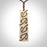 A hand carved, double sided, bone toki with triple koru, intricate pendant. The cord is a brown colour and is adjustable.