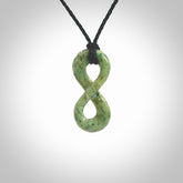 This piece is a fine, delicate eternity shaped pendant. It was carved from a lovely green piece of nephrite jade. It is suspended on an black braided cord that is length adjustable.