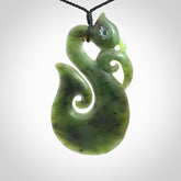 This picture shows a large traditional manaia pendant carved in New Zealand Jade with Paua shell eyes.