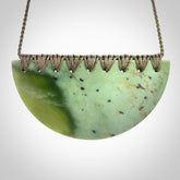 This picture shows a large, hand carved, jade half-shield pendant. The cord is hand plaited and adjustable so that you can position the pendant where it suits you best.