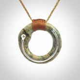 This picture shows a hand carved Nephrite jade circle pendant with sterling silver inlay. It is suspended from an adjustable coloured cord. Delivery is free worldwide.