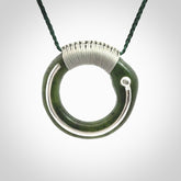 This picture shows a hand carved Nephrite jade circle pendant with sterling silver inlay. It is suspended from an adjustable coloured cord. Delivery is free worldwide.