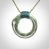 This picture shows a hand carved Nephrite jade circle pendant with sterling silver inlay. It is suspended from an adjustable coloured cord. Delivery is free worldwide.