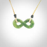 This piece is a fine, delicate eternity shaped pendant. It was carved from a lovely green piece of British Columbian jade. It is suspended on an oat coloured cord that is length adjustable.