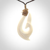 A handcarved hook pendant with a whaletail end. This is carved from bone and is detailed with a traditional Maori engraved design. We will ship this piece to you anywhere in the world and the price for shipping is included in the price. Unique bone jewellery for sale online at www.nzpacific.com