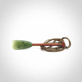 This pendant is a hand carved dragon boat paddle. We have carved this with a Green Nephrite jade blade and a hardwood handle. It is a necklace that was carved for suffered of breast cancer who are members of the Pink Dragons, a group or cancer fighters who take part in Dragon Boat racing events around the world.