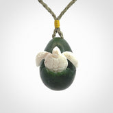 Hand carved turtle hatchling pendant. The egg is carved from green British Columbian jade and the turtle from bone. Designed and carved by NZ Pacific and for sale online.