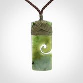This picture shows a small toki pendant with a koru carved into the side. The cord is plaited and is length adjustable. This is a small toki pendant carved from beautiful New Zealand jade.