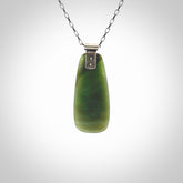 This photo shows a drop pendant suspended from a silver clasp and silver chain. The jade is a lovely light chatoyant Inanga jade with subtle leaf patterned sterling silver on the front. A lovely chatoyant New Zealand Inanga jade pendant carved for us by Josey Coyle.