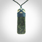 This photo shows a beautiful New Zealand jade toki suspended from a hand plaited adjustable cord. The binding around the top of the toki is a blue and creme colour. The cord is length adjustable which allows the pendant to be positioned where it suits you best. The toki was carved for us by Jen Hung who is a wonderful jade carver from New Zealand.